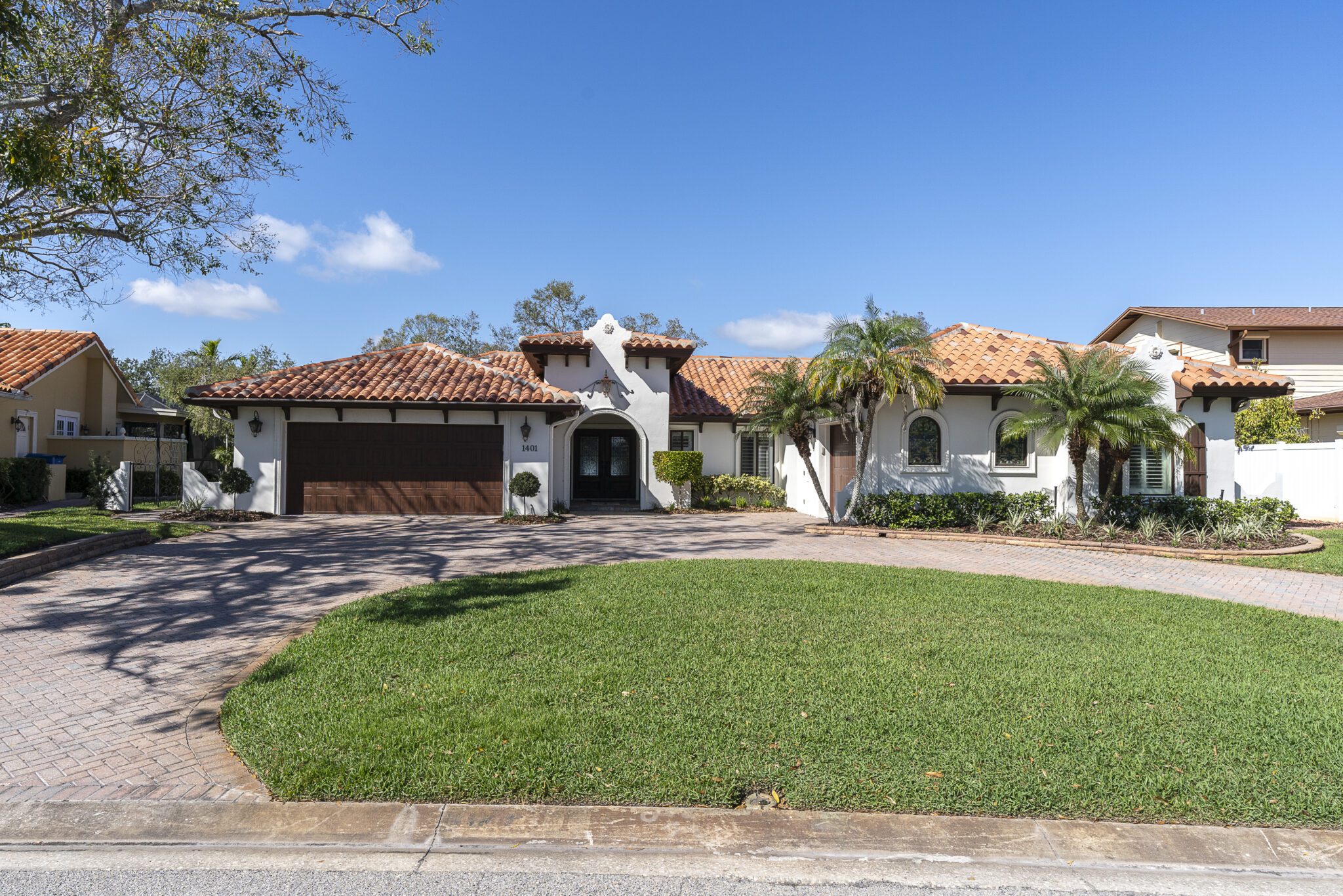 Mediterranean-style home at 1401 75th Circle NE, St. Petersburg, FL, featuring a red tile roof, white stucco exterior, circular driveway, and tropical landscaping in the Harbor Isle neighborhood.